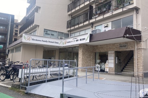 スロープを備えた1階の当院入口と、門戸厄神ひろかわファミリー歯科・矯正歯科の看板